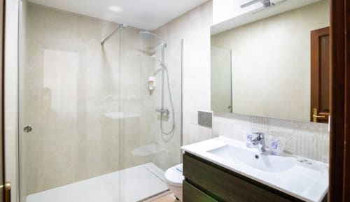 Baño moderno con ducha a ras de suelo, tocador con lavamanos e inodoro en el hotel boutique Zahara de los Atunes de Cádiz