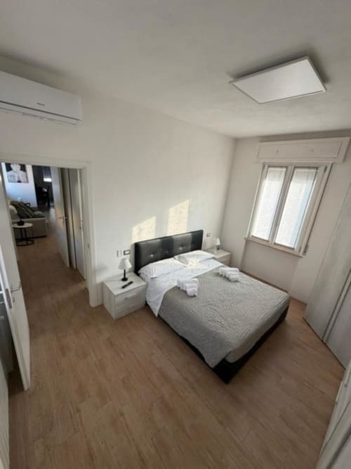 Camera moderna presso MiSaNi Apartments a Novara con letto matrimoniale, pavimenti in legno e luce naturale dalle finestre