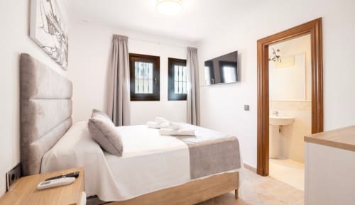 Moderno dormitorio doble en Boutique Zahara de los Atunes con baño ensuite, TV y vistas al pueblo costero