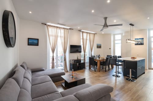 Zen apartment at Enjoy Nice hotel in Nice, France featuring modern living room with gray sofa, dining area, kitchen island,