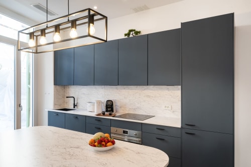 Modern kitchen in Le Zen apartment at Enjoy Nice hotel with dark blue cabinets, marble countertop, and pendant lighting in