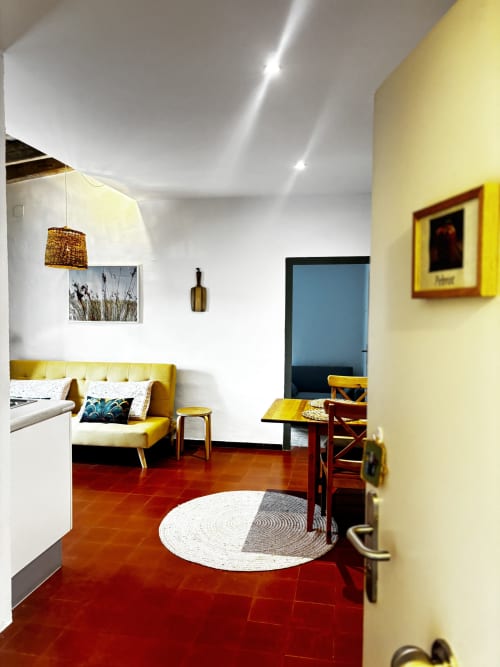 Apartamento Pebrot en el Hotel Mas Ribas de Palamós: salón moderno con sofá amarillo, piso de barro rojo y puerta con vista al jardín