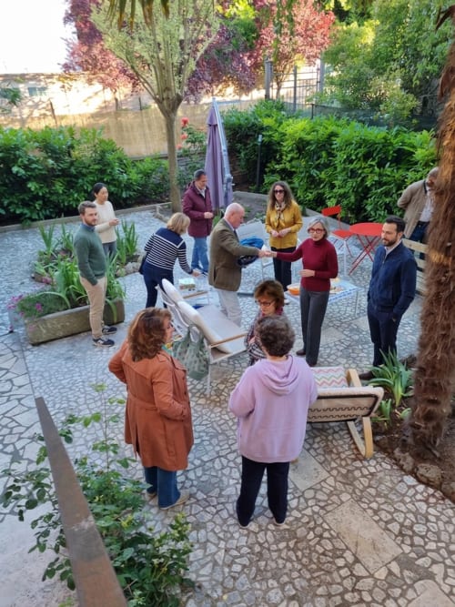 Guests gathering in Cristallo Apartment's courtyard garden in Ravenna, Italy for a social event among lush greenery.
