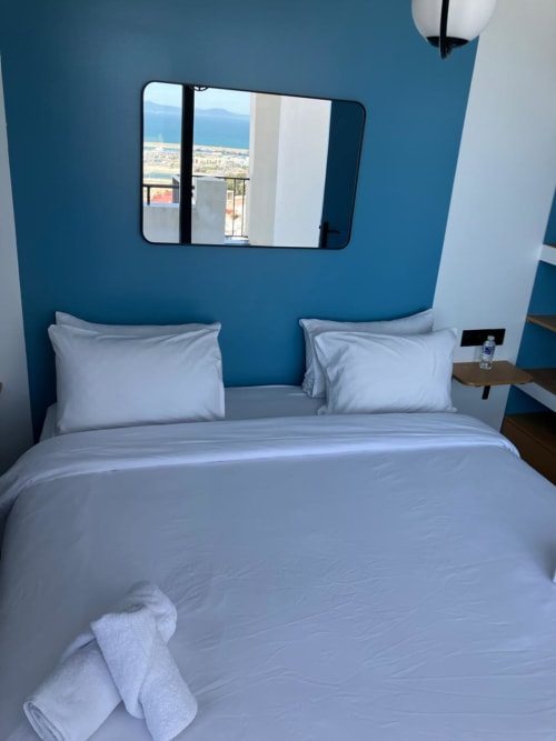 Chambre moderne bleue à l'appartement SAMYAflat Tanger avec balcon vue mer, literie blanche et miroir