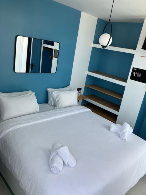 Chambre moderne bleue avec literie blanche à SAMYAflat à Tanger, miroir, étagères et luminaire suspendu