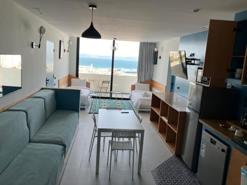 Appartement moderne avec vue sur mer à Tanger, canapé turquoise, coin repas, lits jumeaux, kitchenette, balcon face à la côte