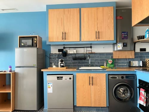 Cuisine moderne dans l'appartement SAMYAflat à Tanger, murs bleus, armoires en bois, appareils en acier inoxydable et lave-vaisselle