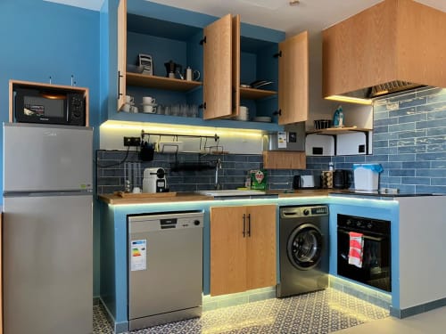Cuisine moderne de l'appartement bleu YaYaCaSa à SAMYAflat Tanger, avec murs bleus, armoires en bois et appareils en acier inoxydable