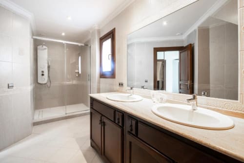 Lujoso baño en el hotel boutique Zahara de los Atunes con lavamanos doble, ducha moderna y encimera de mármol
