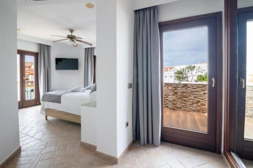 Amplia habitación cuádruple en Boutique Zahara de los Atunes con cama, acceso a terraza y vistas al mar en Cádiz