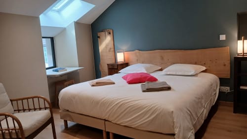 Chambre moderne aux Ateliers du Moulin à Poligny avec lit en bois, mur bleu et puits de lumière