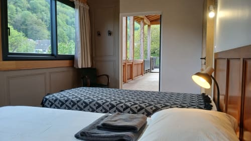 Spacious bedroom at Les Ateliers du Moulin B&B in Poligny with forest views, wooden deck access, and modern amenities