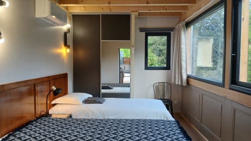 Chambre moderne aux Ateliers du Moulin à Poligny avec poutres apparentes, penderie miroir et vue sur la forêt