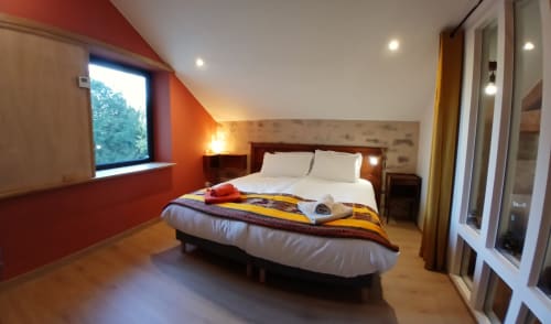 Chambre moderne aux Ateliers du Moulin à Poligny avec murs accentués orange, lit queen-size et décoration contemporaine