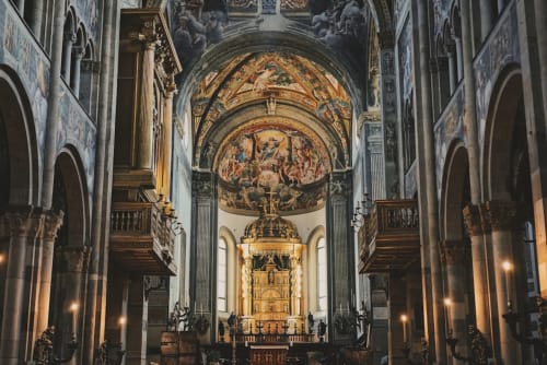 Grand ornate cathedral interior with gilded dome and frescoes in Parma, Italy near Palazzo Garibaldi hotel.