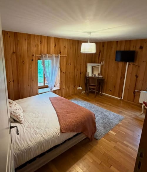 Chambre spacieuse en bois à l'Auberge Du Ruxelier avec lit, TV, bureau et vue sur les montagnes