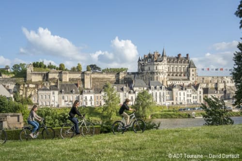 Cyclists riding along Loire river with Château de Montrésor castle backdrop near Beaulieu-les-Loches