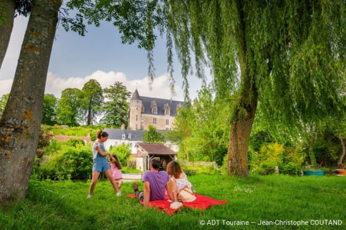 Children playing on grass at Les Troglos de Beaulieu with castle view, Beaulieu-les-Loches France