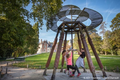 Children playing under modern sculpture in park at Les Troglos de Beaulieu, Beaulieu-les-Loches, France