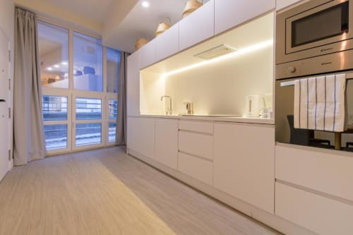 Cocina moderna en la suite Almirante B de Calma Places Sevilla con muebles blancos, electrodomésticos de acero inoxidable y vistas a la ciudad