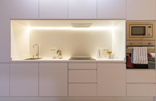 Cocina moderna con muebles blancos, electrodomésticos integrados e iluminación ambiental en el hotel Calma Places de Sevilla