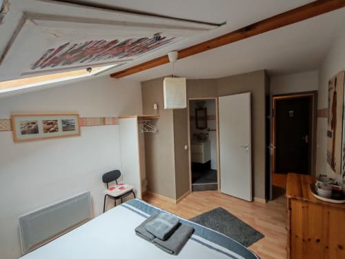 Chambre double lumineuse à La Ressource B&B à Villars-Colmars avec poutres apparentes, lit, armoire et accès salle de bain partagée