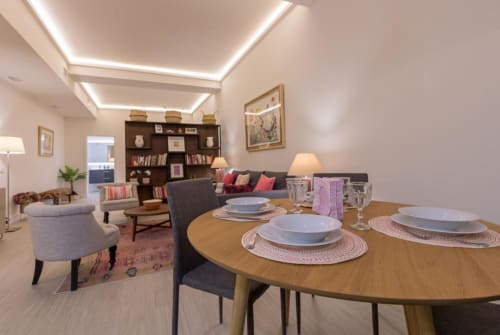 Área de comedor moderna en la habitación Almirante B de Calma Places, Sevilla, con mesa de madera, servicios de mesa y salón