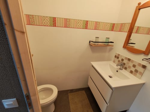 Salle de bain partagée à La Ressource, Villars-Colmars avec toilettes, lavabo, miroir et frise murale décorée