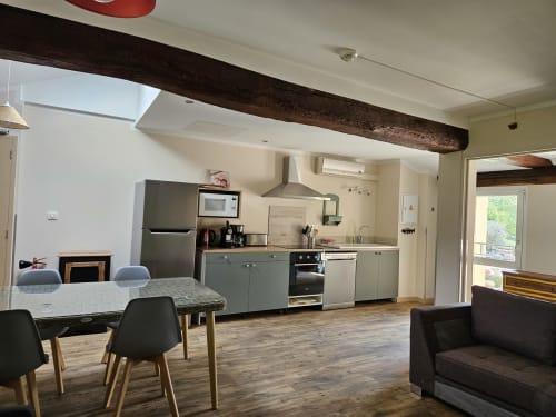 Cuisine ouverte et salle à manger du Gîte Eglantine, Gites Les Muriers, avec mobilier gris moderne et acier inoxydable