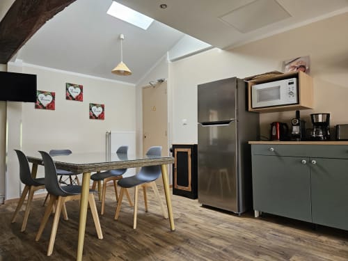 Cuisine-salle à manger moderne au Gîte Eglantine à Bourgvilain avec table à manger, appareils en acier inoxydable et touches de vert
