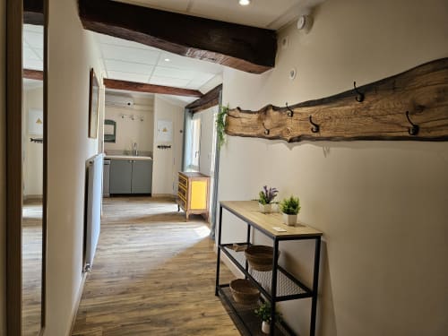 Couloir moderne aux Gîtes Les Muriers à Bourgvilain avec poutres rustiques, console et entrée de cuisine.