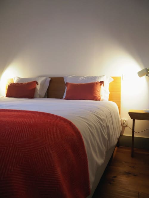 Quarto aconchegante da quinta com roupa de cama branca, almofadas vermelhas e iluminação quente em Arcos de Valdevez