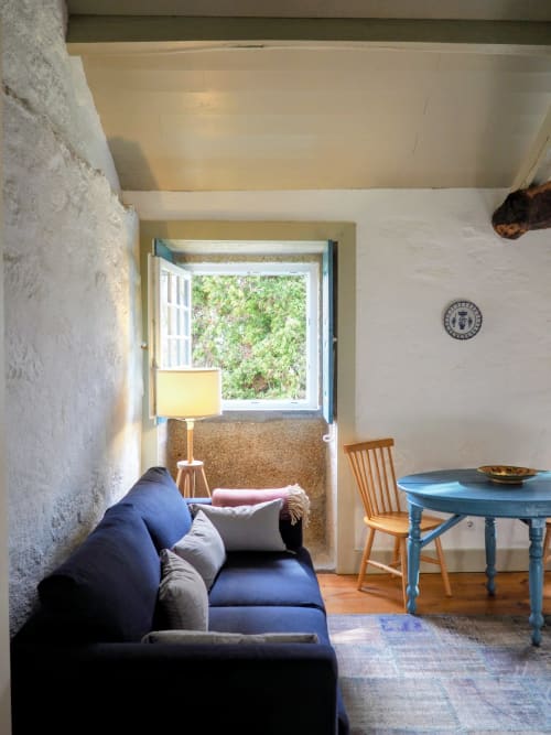 Aconchegante sala de estar com sofá azul, mesa de madeira e vistas para o jardim na Quinta da Coutada, Arcos de Valdevez