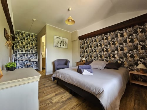 Chambre moderne aux Gîtes Les Muriers à Bourgvilain avec lit queen-size, tête de lit motifs, coin détente et vue sur le jardin