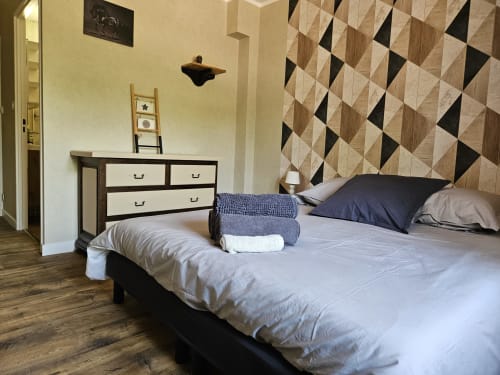 Chambre du Gîte Le Tilleul avec lit queen-size, mur d'accent géométrique, commode et serviettes pliées aux Gîtes Les Muriers, Bourgvilain