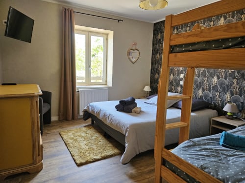 Chambre spacieuse aux Gîtes Les Muriers avec lits superposés jumeaux en bois, bureau et vue sur le jardin à Bourgvilain