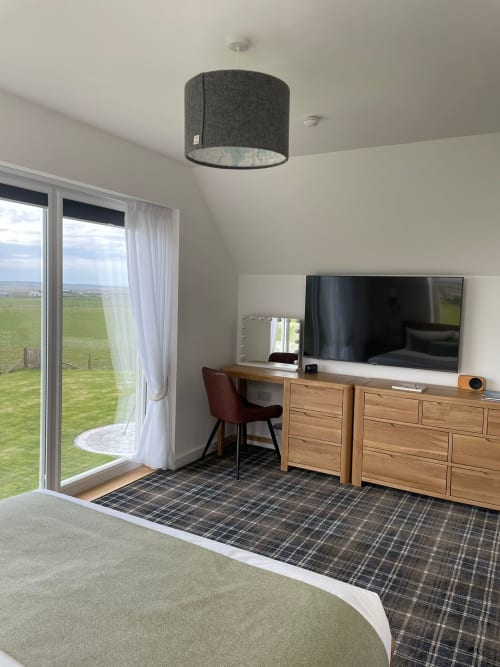 Modern bedroom at Flotnar Hus B&B in Keiss with countryside views, wooden furniture, and pendant lighting