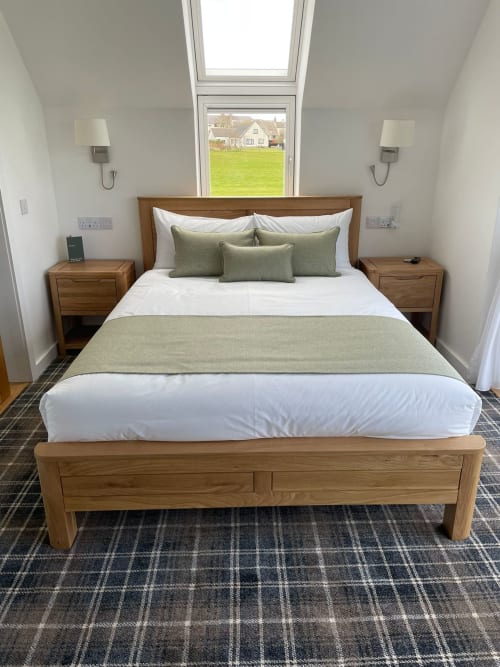 Bright bedroom at Flotnar Hus B&B in Keiss with wooden bed, green bedding, skylights, and countryside views