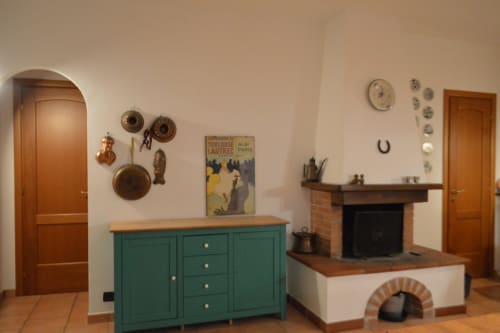 Interno rustico di appartamento a Villa Collebelvedere con mobile verde, camino in mattoni e arredamento vintage a Fara In Sabina