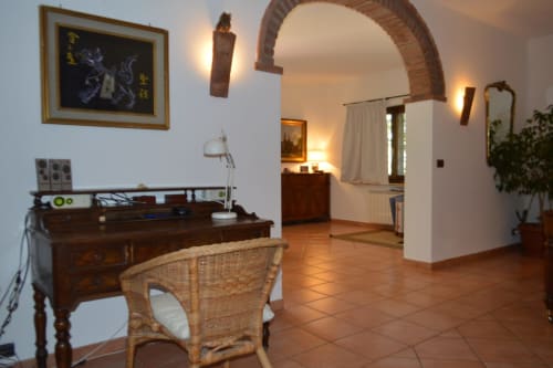 Ampio interno dell'appartamento a Villa Collebelvedere con scrivania in legno, sedia di vimini, pavimenti in cotto e volta in mattoni a Fara