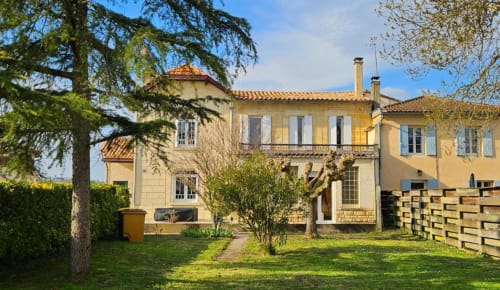 Château Le Conte gîte in Saint-Emilion with cream stone facade, terracotta roof, manicured garden, and mature trees