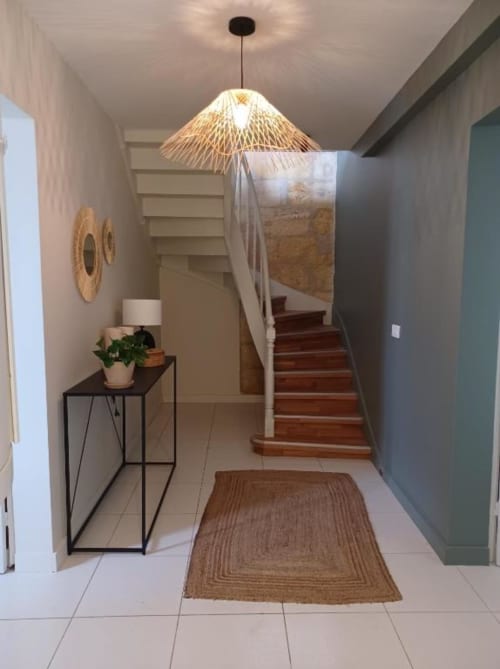 Modern entryway at Château Le Conte with woven pendant light, wooden staircase, and decorative console table with plant