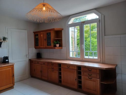 Rustic kitchen with wooden cabinets, woven pendant light, and garden views at Saint-Emilion B&B
