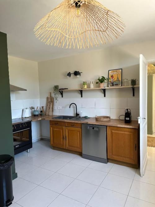 Modern kitchen with wooden cabinets, white tile backsplash, and brass pendant light at Château Le Conte, Saint-Emilion