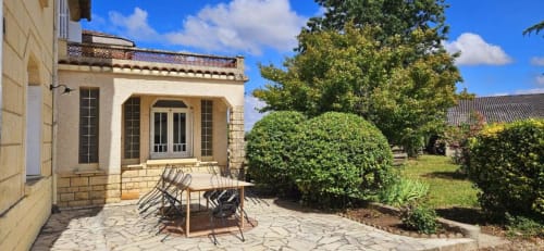Stone terrace with lounge chairs overlooking lush gardens at Château Le Conte guesthouse, Saint-Émilion