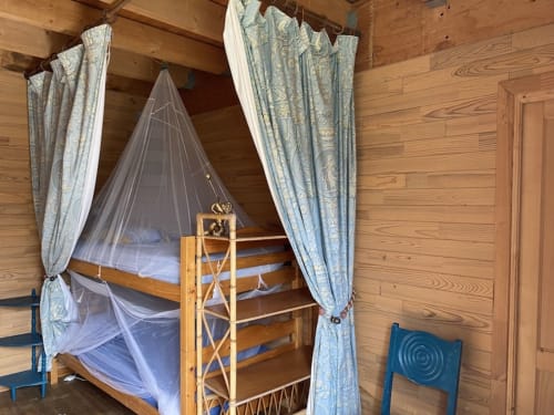 Wooden bedroom with four-poster bed, sheer canopy, blue patterned curtains at Le Lama Zébré B&B in Penmarch