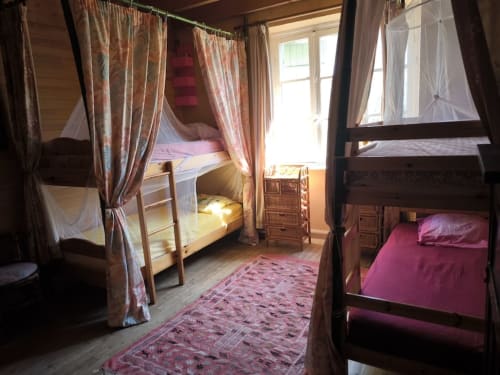 Shared bedroom at Le Lama Zébré BnB in Penmarch with canopy beds and pink linens