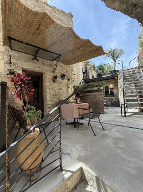Beschattete Terrasse des Ferienstudios „Occitan Heritage“ in La Sarrasine in Aiguèze, mit blühenden Pflanzen und Panoramablick auf die Stadtmauern.
