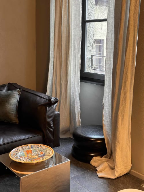 Zona living moderna con poltrona in pelle nera, pouf, piatto decorativo e vista sulla città presso Casa_B Como