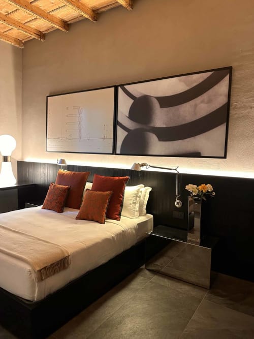 Camera da letto elegante dell'appartamento Casa_B Como City con letto color crema, cuscini color ruggine, travi in legno e opere d'arte moderna alle pareti